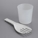 A white plastic measuring cup with a plastic spoon.