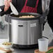 A man using an Avantco electric rice warmer to serve himself rice and peas.