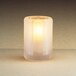 A lit Sterno Paragon frosted fluted candle holder on a table.