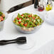 A Carlisle Petal Mist clear bowl filled with salad with tomatoes and croutons.