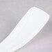A close up of a Fineline Tiny Tensils white plastic spoon with a rectangular handle.