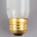 A close up of a Satco T10 incandescent light bulb with a gold base and frosted finish.