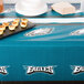A Philadelphia Eagles plastic table cover on a table with food.