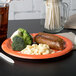 A Cincinnati Bengals paper dinner plate with sausage and broccoli on it.