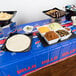 A table with Buffalo Bills themed party supplies on it with bowls of food and a tortilla plate.
