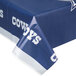A blue and white Creative Converting Dallas Cowboys plastic table cover with white writing on a table.