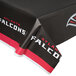 A black plastic table cover with red and white Atlanta Falcons logos on a table.
