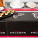 A table with an Atlanta Falcons table cover on it with food.