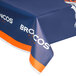 A blue and orange Creative Converting Denver Broncos plastic table cover with white writing on a table.