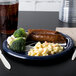 A Seattle Seahawks paper dinner plate with sausage and broccoli on it.