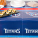 A table with a Tennessee Titans tablecloth and plates of food.