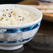 A blue Thunder Group melamine rice bowl filled with white rice and black sesame seeds.
