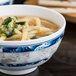 A blue Thunder Group Blue Dragon melamine bowl filled with soup, noodles, and vegetables.