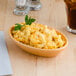 A brown Tuxton oval baker filled with macaroni and cheese on a table.