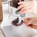 A person pouring coffee beans into a Zevro SmartSpace countertop dry food dispenser.