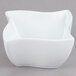 An American Metalcraft Prestige white porcelain bowl with a curved edge on a gray surface.
