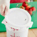 A gloved hand holds a Choice white polypropylene food storage container lid.