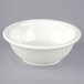 A Tuxton eggshell white china footed salad bowl on a gray surface.