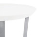 A white round tray with 3 silver legs on a white table.
