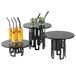 A group of black round tables with drinks on them using a round black tempered glass riser shelf.