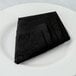 A folded black Hoffmaster FashnPoint linen-feel napkin on a white plate.