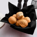 A bowl of rolls on a black Hoffmaster Linen-Feel napkin.