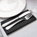 A knife and fork on a black Hoffmaster FashnPoint linen-feel napkin.
