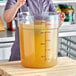 A woman mixing a liquid in a large Choice clear round food storage container.