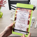 A hand holding a customizable wood menu board with lime rubber band straps.