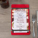 A customizable wood menu board with rubber band straps on a table with a menu on it.