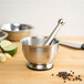 A Fox Run stainless steel mortar and pestle set on a wooden table.