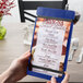 A close-up of a blue Menu Solutions wood menu board with rubber band straps.
