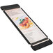 A black Menu Solutions wood menu board with rubber bands holding a menu.