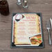 A customizable wood menu board on a table with a glass and a fork.
