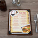 A Menu Solutions customizable wood menu board on a table with a fork and knife.
