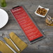 A customizable wood menu clip board on a table with a menu, fork, and knife.