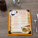 A Menu Solutions customizable wood menu board on a table with a picture of food inside.