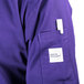 A person wearing a Mercer Culinary purple cook jacket with a white label on the pocket.