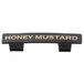 A black Tablecraft dispenser tag with gold text reading "Honey Mustard"