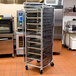 A black Curtron breathable mesh cover on a large metal rack with trays in a kitchen.