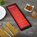 A Menu Solutions walnut wood clip board holding a menu on a table with a fork and knife.