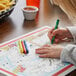 A child coloring on a paper with Choice restaurant crayons.
