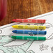 A group of Choice triangular kids' restaurant crayons on a red surface.