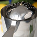 A Barfly stainless steel scalloped julep strainer on a counter.