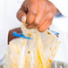 A hand using a blue San Jamar Bag Boa to hold a plastic bag of food.