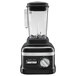 A close-up of a matte black KitchenAid blender with a clear glass container.