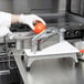 A person in white gloves using a Vollrath Redco Tomato Pro slicer to cut a tomato.