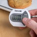 A person using a Taylor digital kitchen timer to measure a cookie.