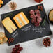 A black rectangular slate board with cheese and meat on it.