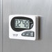 A white Taylor digital kitchen timer with black numbers on a silver surface.